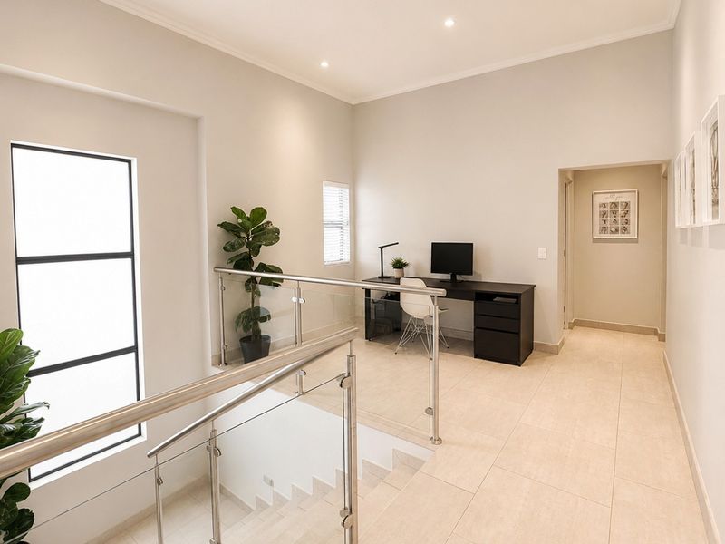 A bright and modern landing area featuring a glass balustrade with stainless steel handrails and neutral tiled flooring.