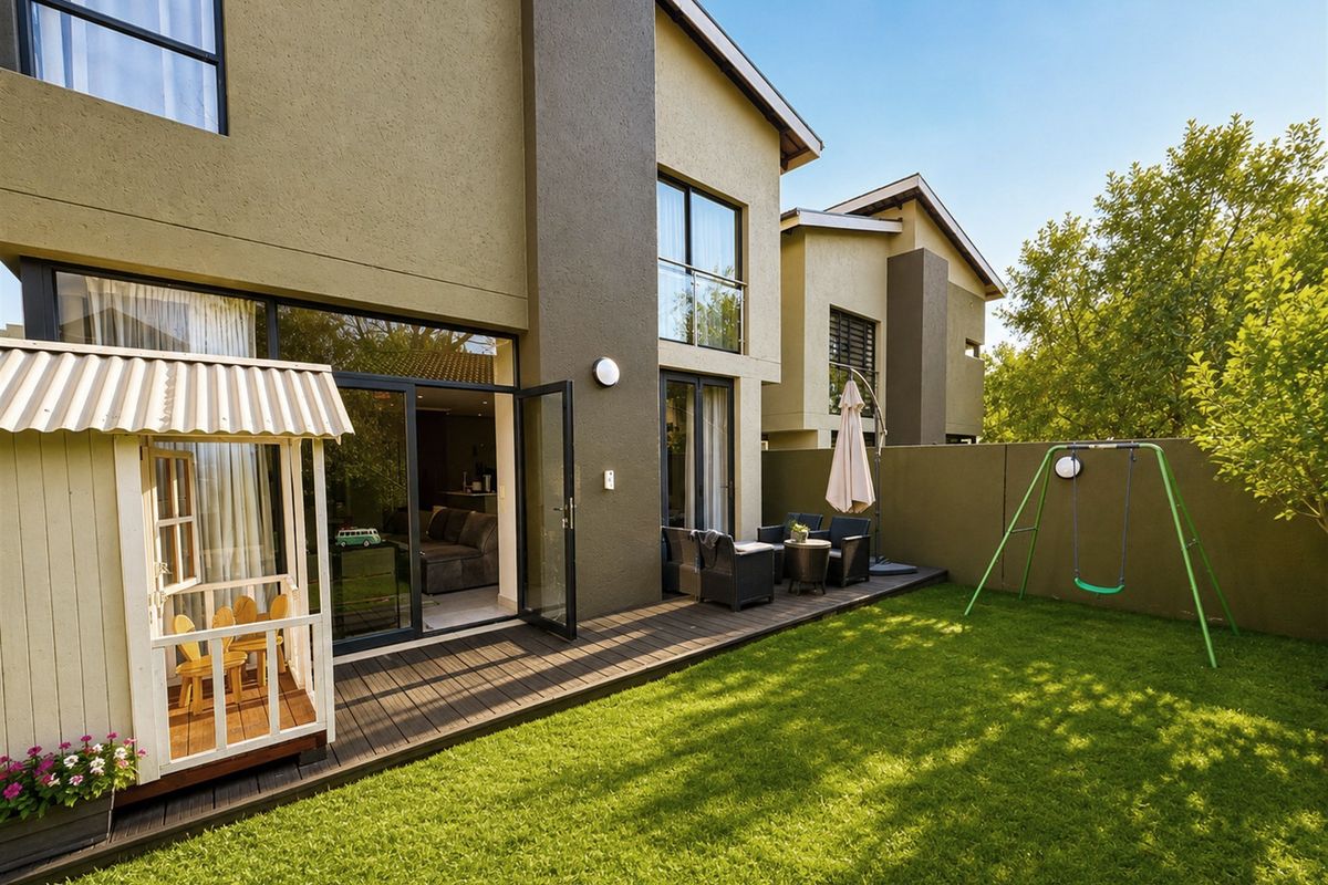 Rear view of the property featuring a timber deck, landscaped garden, and direct access to the interior living spaces through large glass doors.