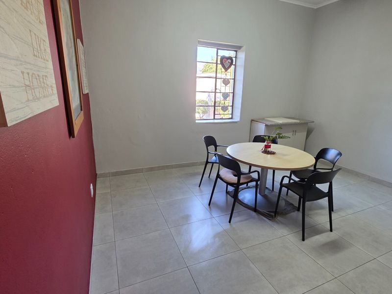 A dining area featuring tiled flooring, a window with security bars, and a small built-in cabinet.