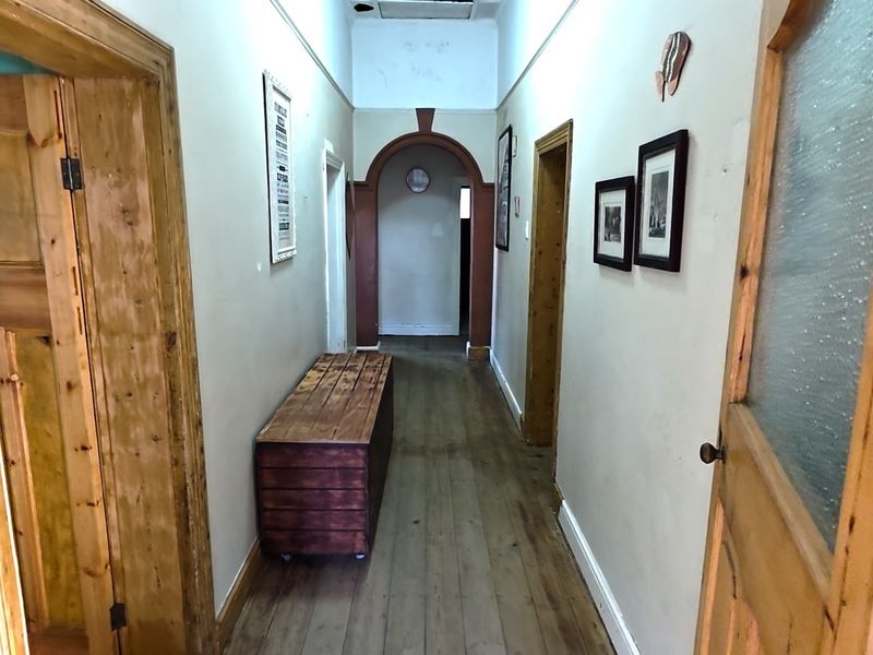A traditional hallway featuring timber flooring, classic archway detailing, and multiple timber door frames leading to adjacent rooms.