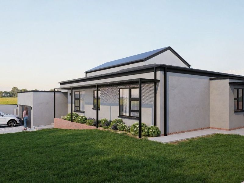 A modern single-story house exterior featuring a metal roof, covered patio area, paved driveway, and a secure perimeter wall.