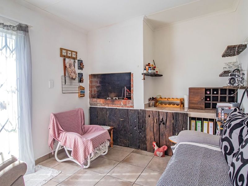 Living area featuring a built-in indoor braai with rustic timber cladding and tiled flooring, providing a cozy space for indoor entertaining.
