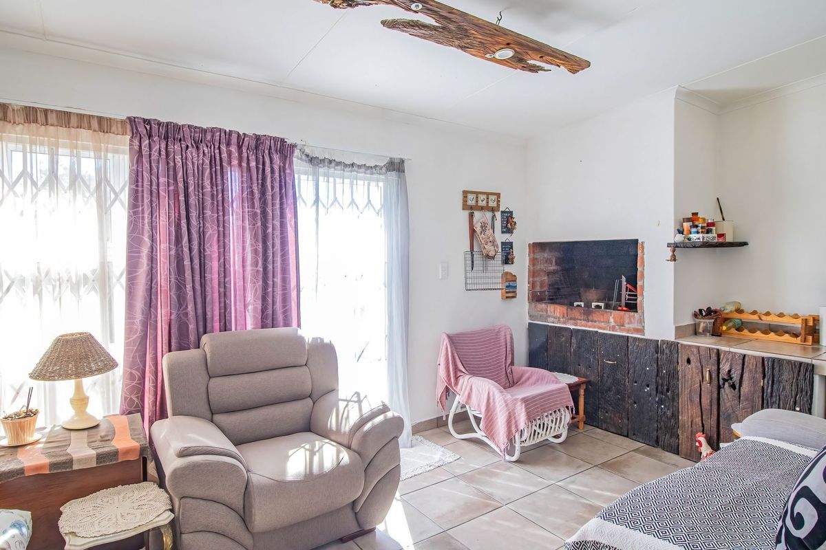 A living room featuring a built-in brick fireplace, tiled flooring, and sliding glass doors providing access to the exterior.