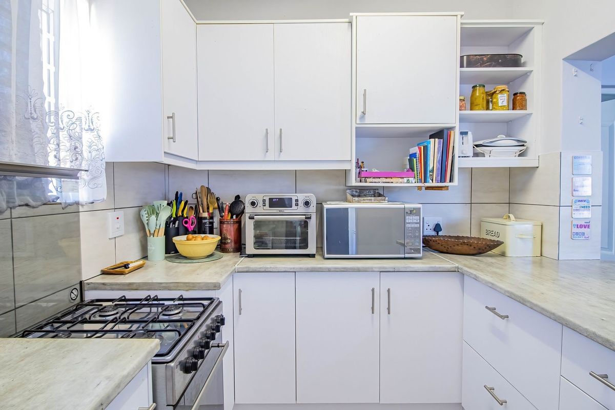 A functional kitchen featuring white cabinetry, laminate countertops, a gas stove, and a tiled backsplash, offering a clean and practical workspace.