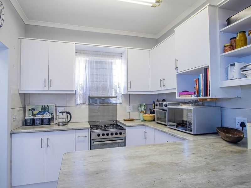 A functional kitchen featuring white built-in cabinetry, a gas stove with extractor fan, and durable laminate countertops with a tiled backsplash.