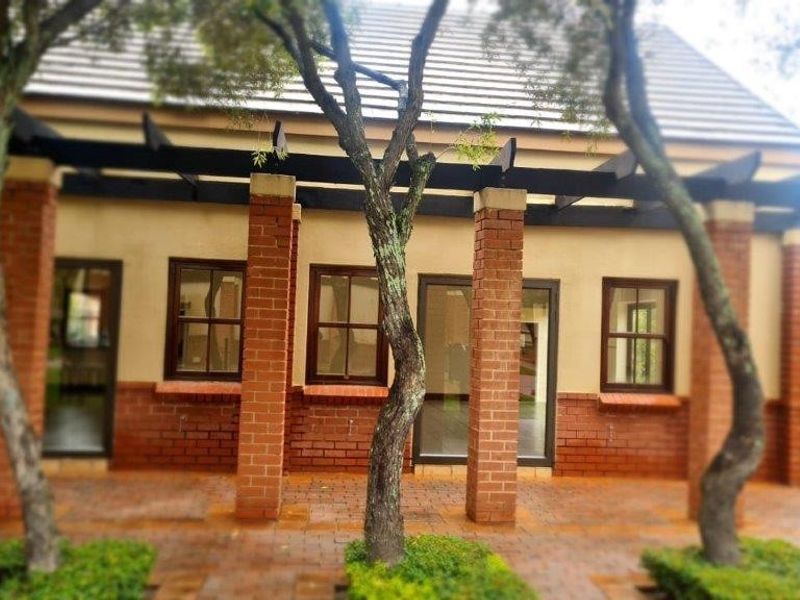A covered outdoor patio area featuring brick pillars, a timber pergola, and paved flooring, providing a seamless transition to the garden.