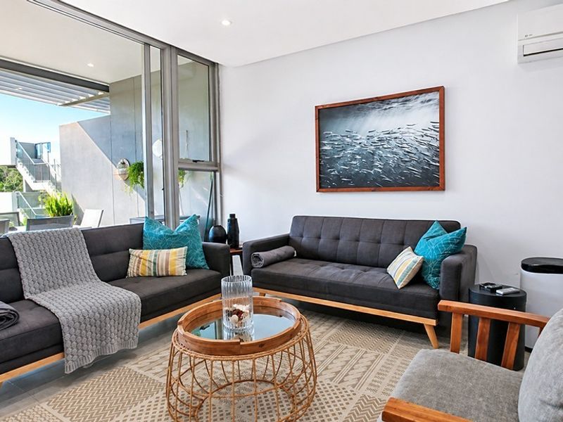 Modern living room featuring large sliding glass doors leading to a balcony, recessed lighting, and a wall-mounted air conditioning unit.
