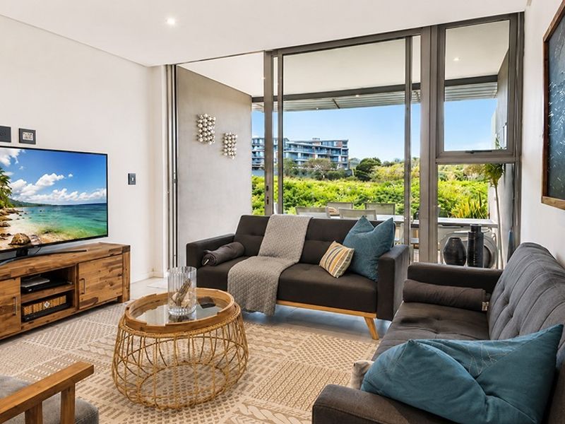 Modern living room featuring large sliding glass doors that open onto a balcony, providing ample natural light and seamless indoor-outdoor flow.