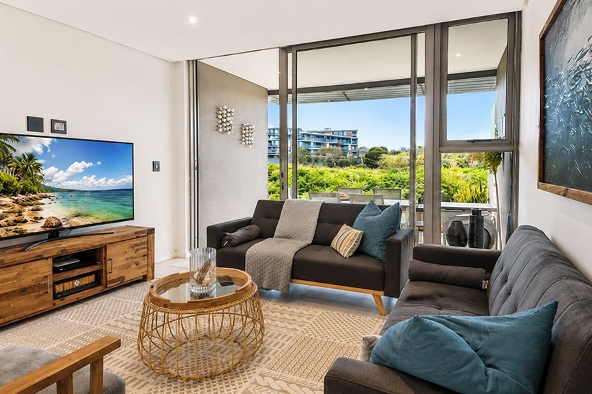 Modern living room featuring large sliding glass doors that open onto a balcony, providing ample natural light and seamless indoor-outdoor flow.