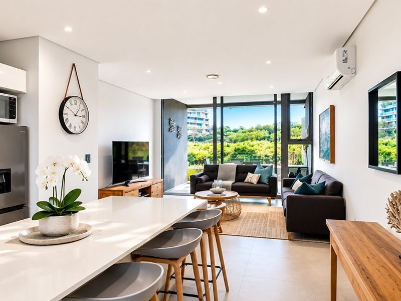 Modern open-plan living area featuring a sleek kitchen island, tiled floors, and floor-to-ceiling windows that provide abundant natural light and scenic views.