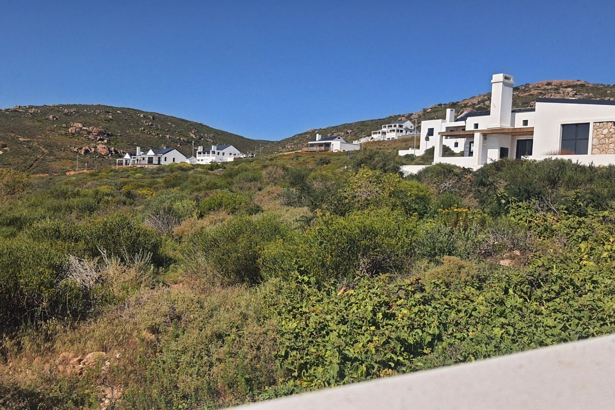 A scenic view of the residential estate landscape featuring natural coastal vegetation and surrounding hillside properties.