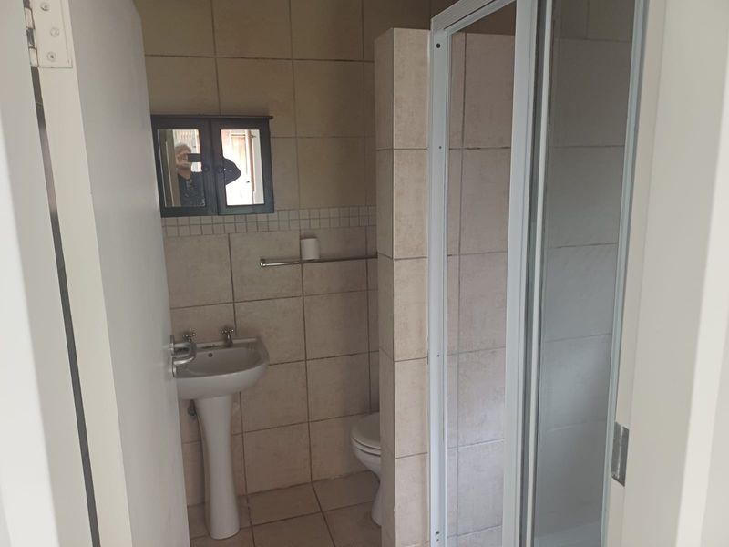 A functional bathroom featuring a pedestal basin, toilet, and a separate shower enclosure with tiled finishes throughout.