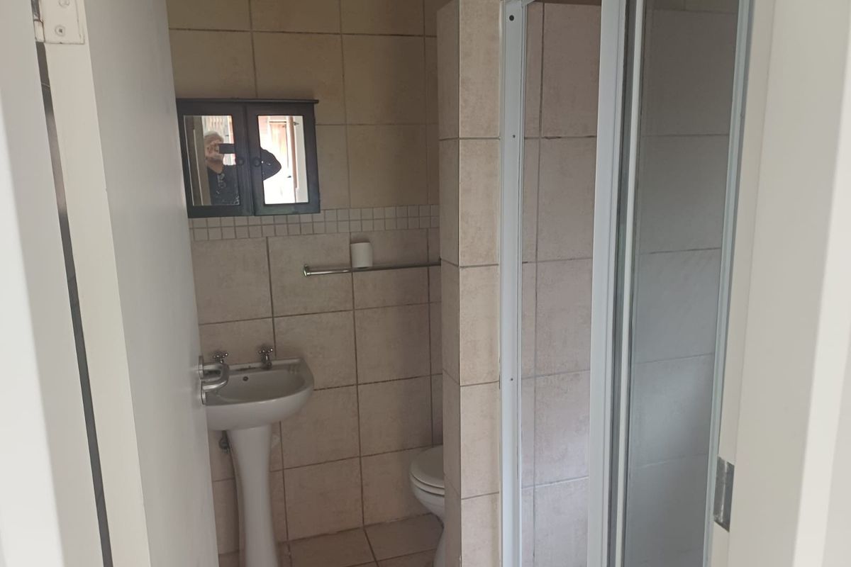 A functional bathroom featuring a pedestal basin, toilet, and a separate shower enclosure with tiled finishes throughout.