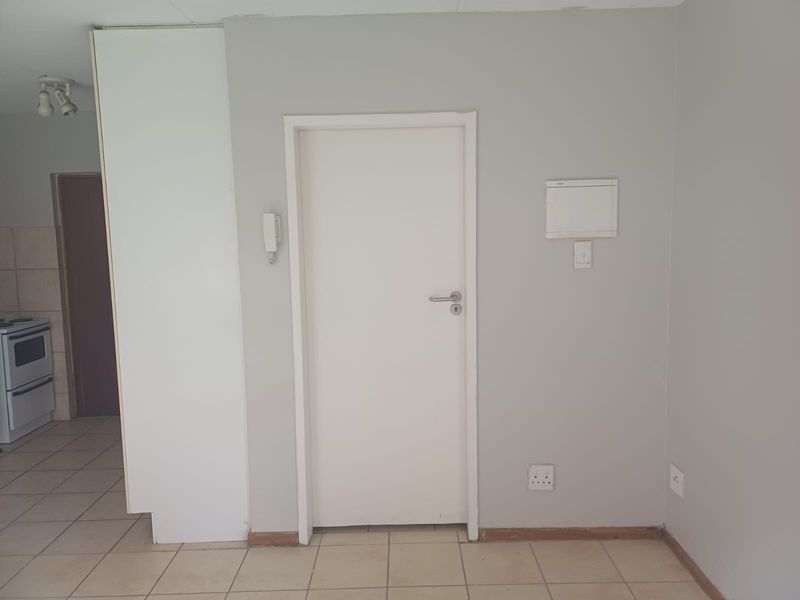 A functional hallway area featuring tiled flooring, an intercom system, and access to adjacent rooms, presented in a clean, neutral condition.