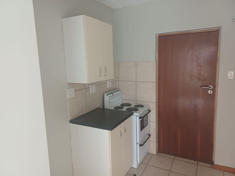 Compact kitchen area featuring basic cabinetry, tiled splashback, and a freestanding stove, providing a functional foundation for a modern update.