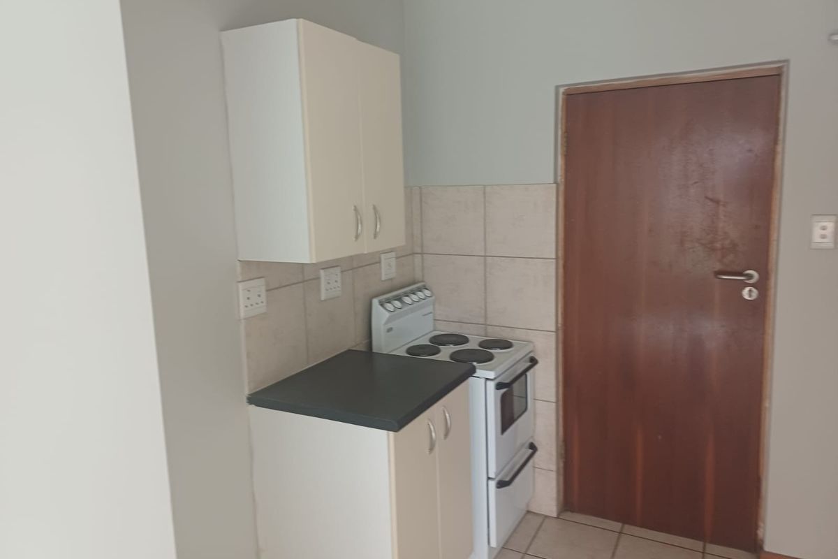 Compact kitchen area featuring basic cabinetry, tiled splashback, and a freestanding stove, providing a functional foundation for a modern update.