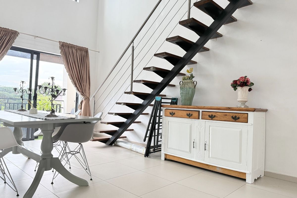 Bright living area featuring an open-tread staircase with metal balustrades, tiled flooring, and large sliding glass doors leading to an outdoor space.