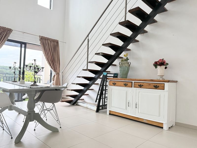 Bright living area featuring an open-tread staircase with metal balustrades, tiled flooring, and large sliding glass doors leading to an outdoor space.
