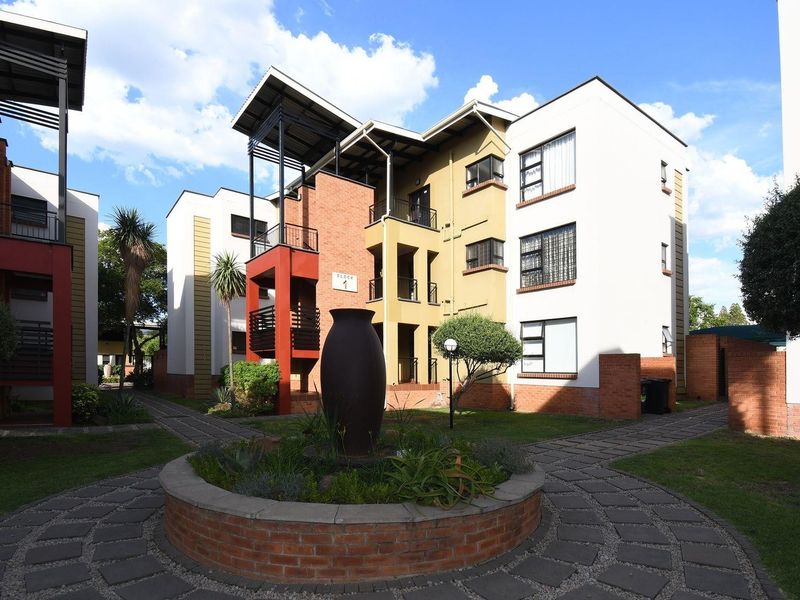 Exterior view of a modern apartment complex featuring brick and rendered facades, private balconies, and well-maintained landscaped garden pathways.