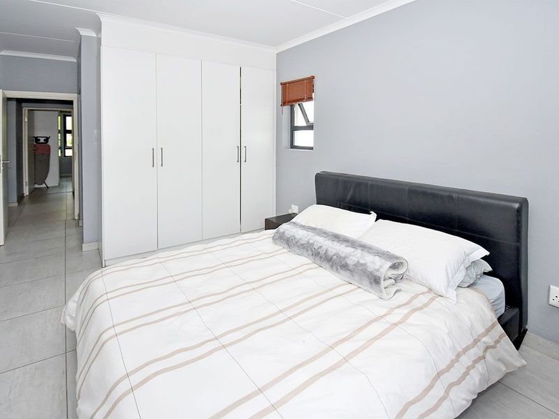 A well-maintained bedroom featuring neutral grey walls, tiled flooring, and ample built-in cupboard storage.