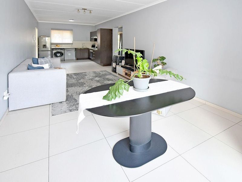 Open-plan living and kitchen area featuring neutral tiled flooring and modern cabinetry, providing a functional and versatile space for daily living.