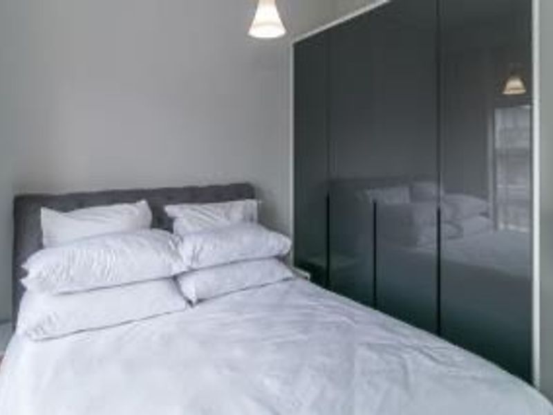 A modern bedroom featuring a sleek, dark grey built-in wardrobe and neutral wall finishes.
