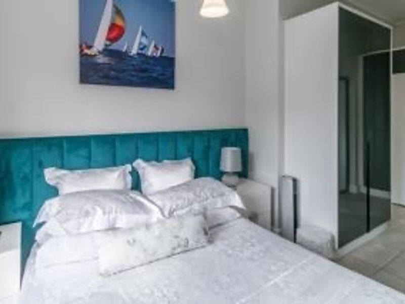 A well-maintained bedroom featuring a modern built-in wardrobe with mirrored doors and neutral tiled flooring.