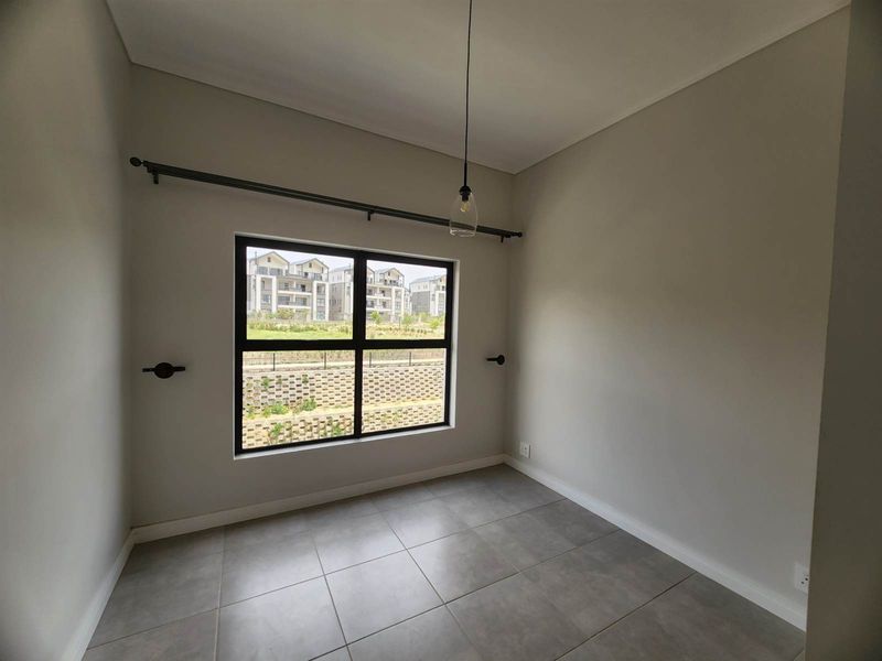 A clean, empty bedroom featuring neutral wall tones, large black-framed windows, and modern tiled flooring, ready for personalization.