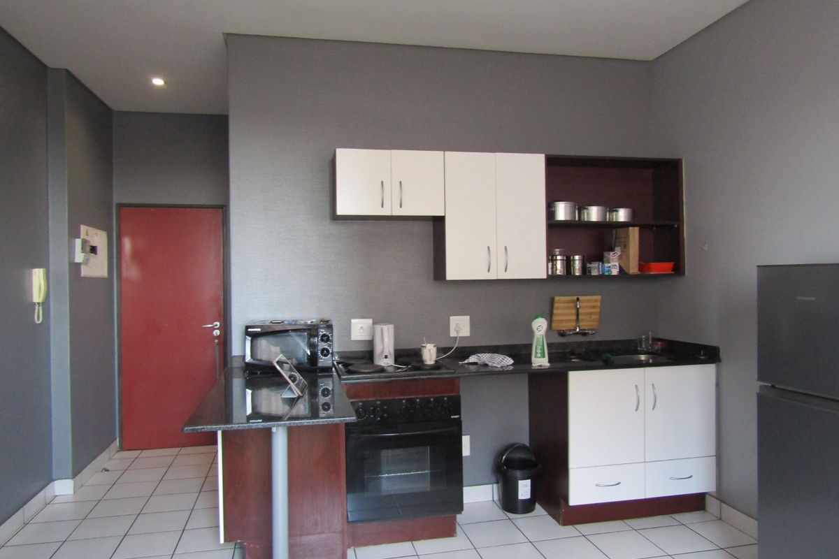 Compact kitchen featuring built-in cabinetry, granite countertops, an electric oven, and tiled flooring, providing a functional workspace within the apartment.