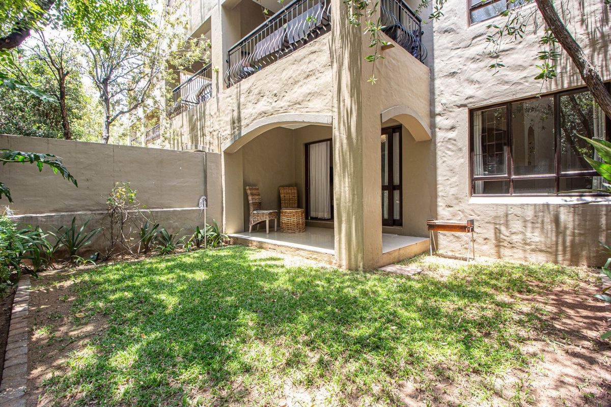 Ground floor apartment featuring a private covered patio and a small garden area with established trees and boundary walling.
