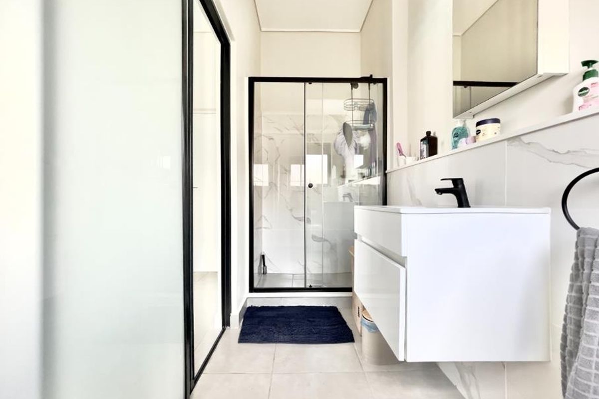 Modern bathroom featuring a floating vanity with a black faucet, a glass-enclosed shower, and contemporary marble-look wall tiling.