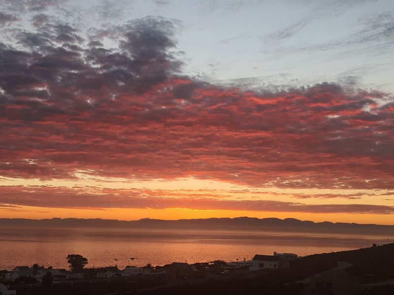 A scenic sunset view overlooking the coastline and distant mountain range, showcasing the natural beauty of the surrounding landscape.