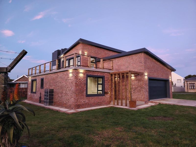 Modern face brick house featuring a double garage, upper-level balcony with timber railing, and a timber pergola entrance.