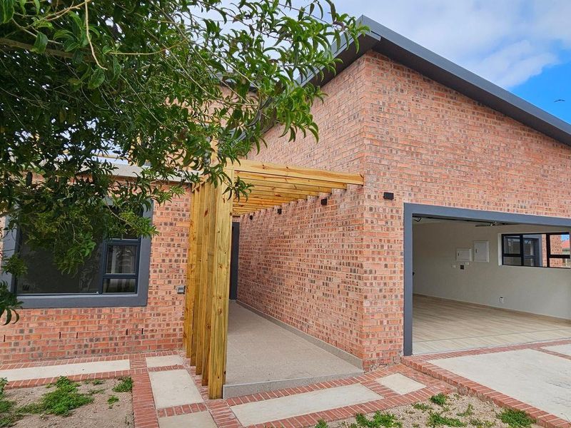 Modern face brick home featuring a timber pergola entrance and an integrated double garage with a concrete driveway.