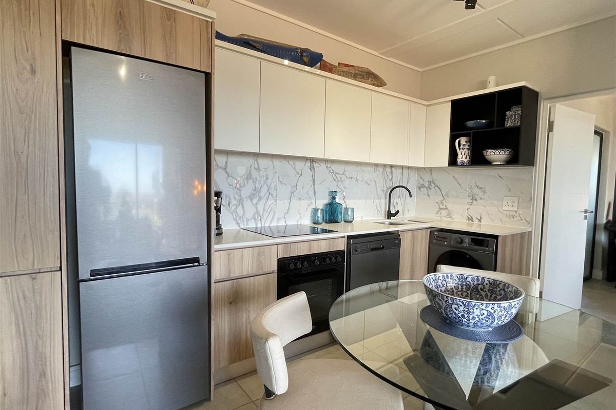 Modern kitchen featuring wood-grain and white cabinetry, marble-look splashback, integrated oven, and hob, offering a clean and functional cooking space.