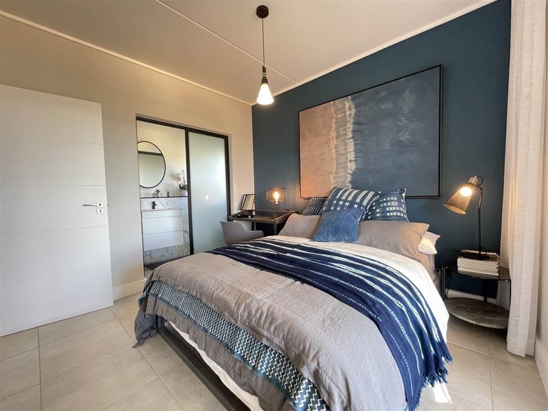 A well-maintained bedroom featuring tiled flooring, a feature wall, and direct access to an en-suite bathroom.