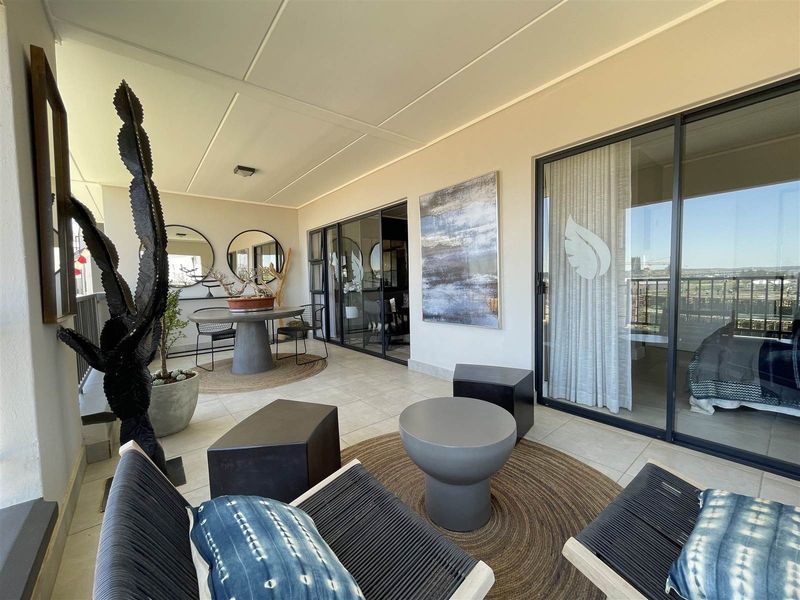 A spacious covered balcony featuring tiled flooring and large sliding glass doors, providing a seamless transition between indoor and outdoor living areas.