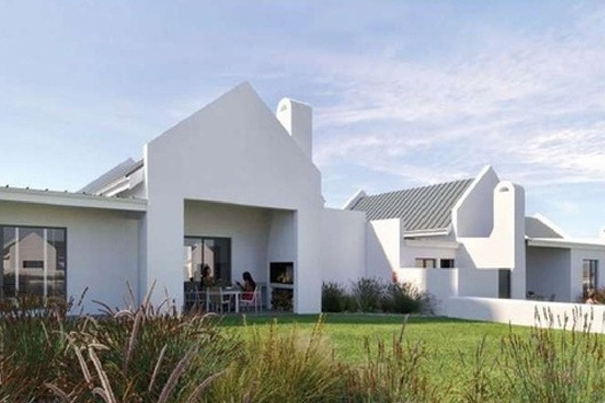 Rear view of a modern white house featuring a covered patio with a built-in fireplace, metal roofing, and a well-maintained garden.