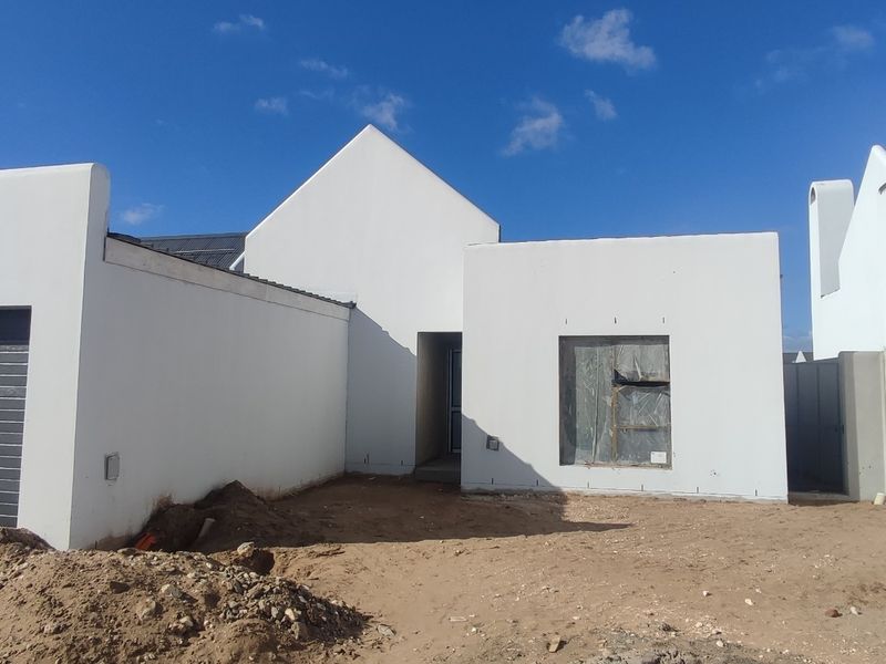 Front elevation of a modern house under construction, featuring a garage, plastered white walls, and unfinished landscaping.