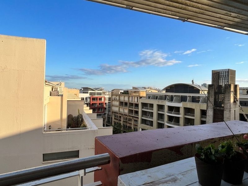 An elevated urban view overlooking surrounding apartment buildings from a balcony with a metal railing and painted parapet wall.