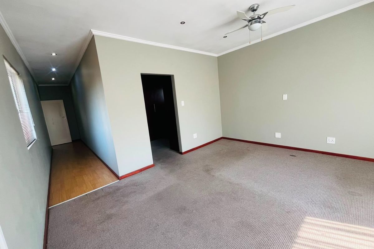 An empty bedroom featuring neutral wall tones, a ceiling fan, recessed lighting, and a combination of carpet and laminate flooring.
