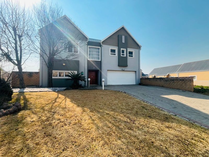 Front elevation of a two-story residential house featuring a paved driveway, double garage, and landscaped front garden area.