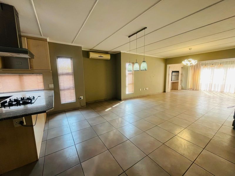 Spacious open-plan living and kitchen area featuring tiled floors, modern cabinetry, granite countertops, and integrated lighting, offering a versatile layout for dining and relaxation.