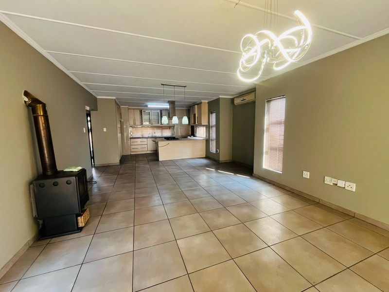 Spacious open-plan living and kitchen area featuring tiled floors, a modern fireplace, and a functional kitchen layout with built-in cabinetry.