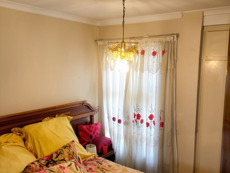 A cozy bedroom featuring a built-in wardrobe, decorative ceiling coving, and a central light fixture, offering a functional and comfortable sleeping space.