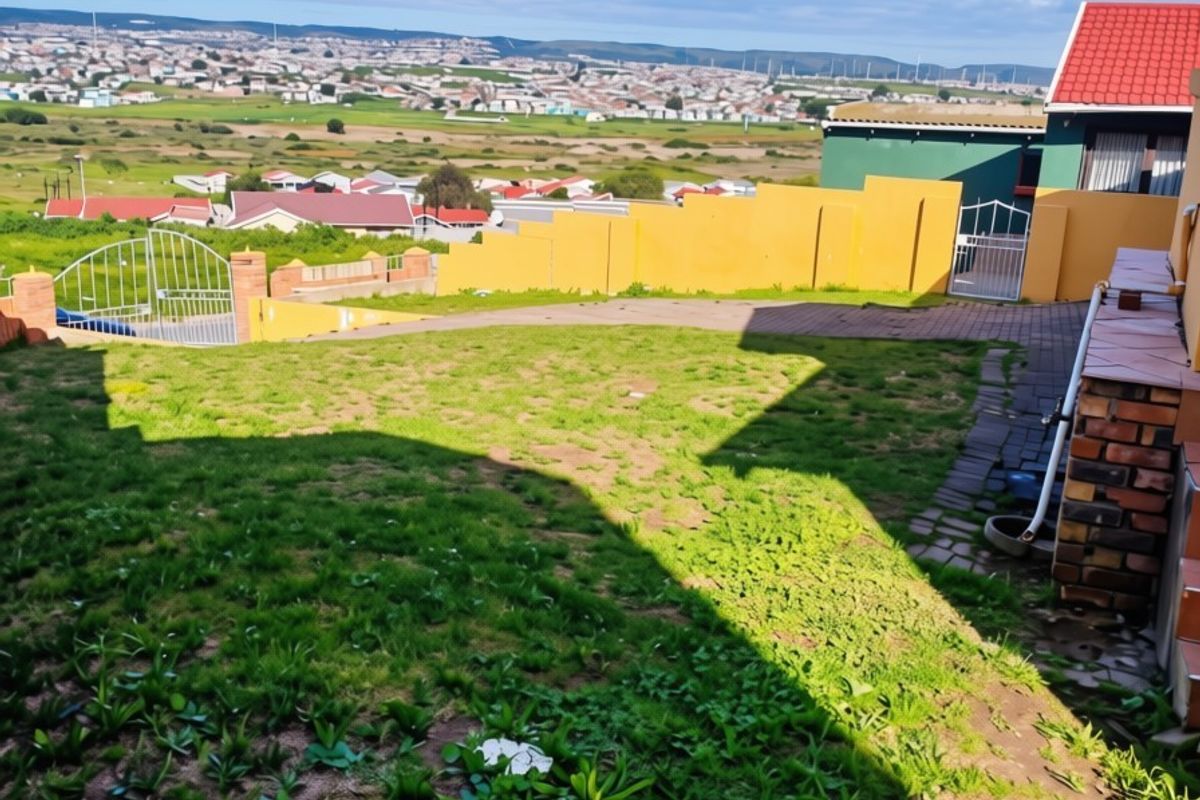 A rear garden area featuring a paved driveway, brick boundary walls, and expansive views over the surrounding residential landscape.