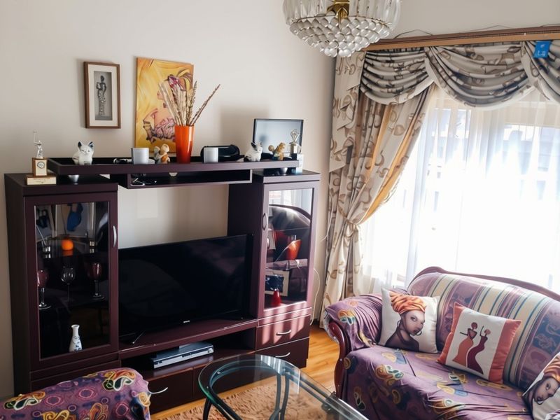 A cozy living room featuring hardwood flooring, a decorative crystal chandelier, and classic window treatments, offering a comfortable and traditional living space.