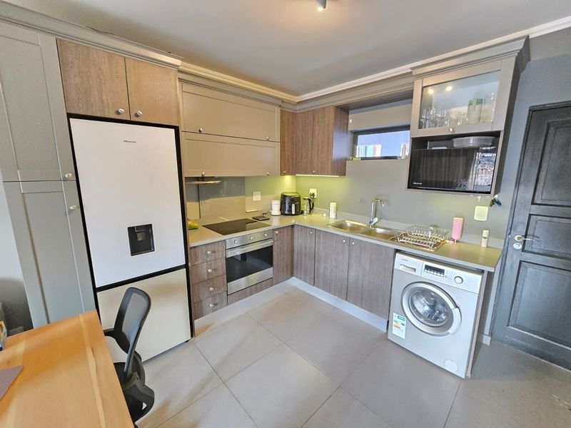 Modern kitchen featuring wood-tone and grey cabinetry, stone countertops, integrated appliances, and tiled flooring in a functional, well-maintained layout.