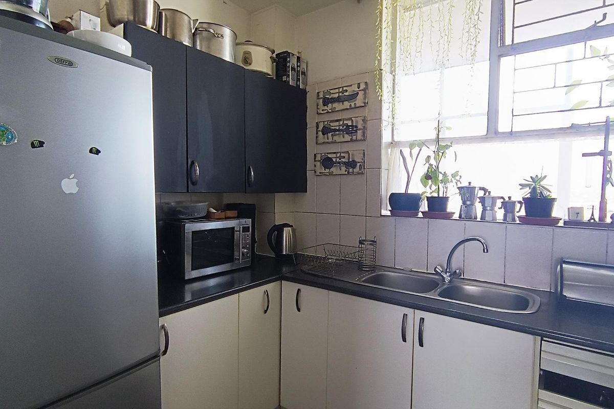 A functional kitchen featuring dark upper and light lower cabinetry, a double bowl sink, and a tiled backsplash with natural light from the window.