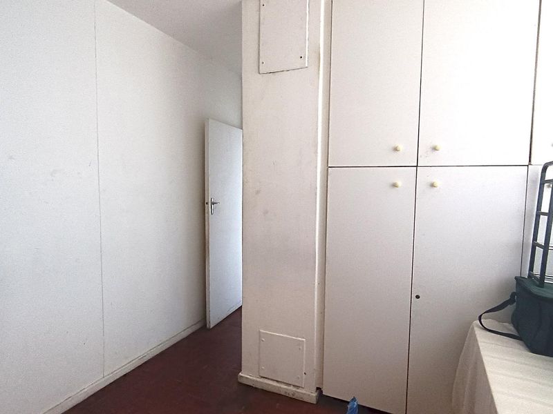 A functional hallway area featuring built-in storage cupboards and access to an internal room.